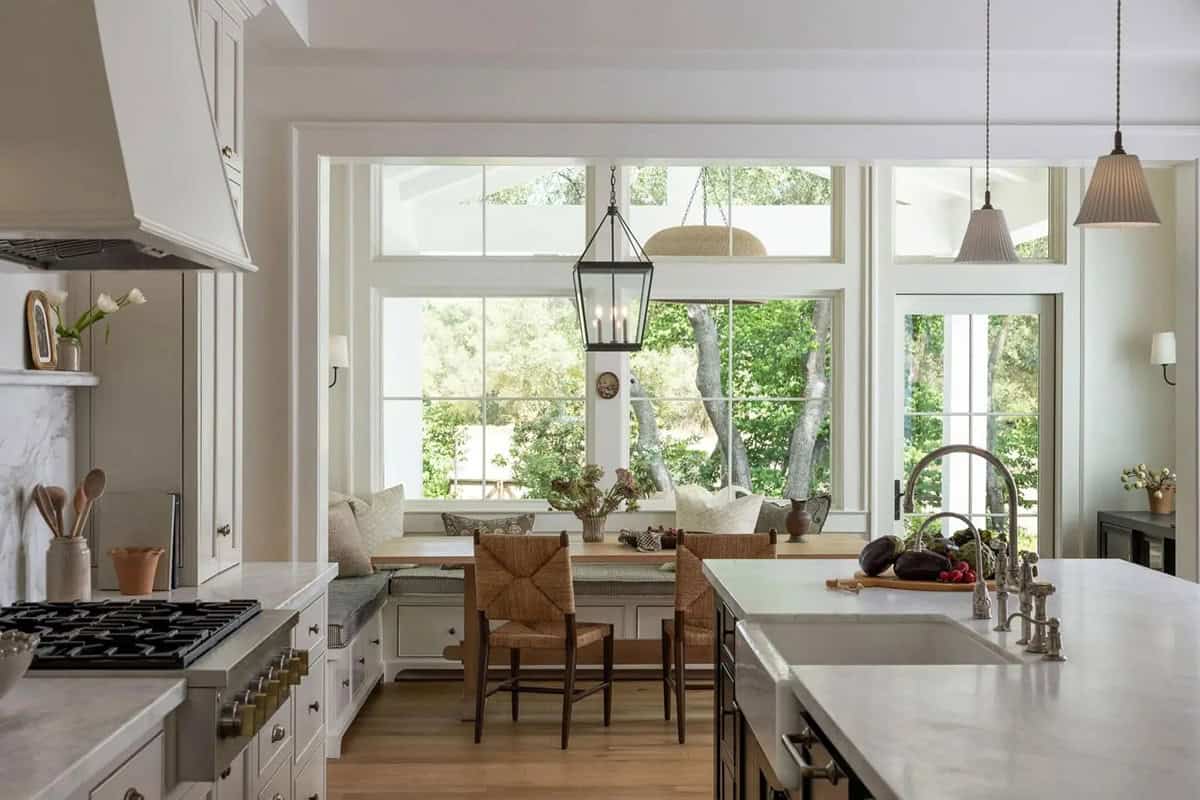 Kitchen breakfast nook with built-in window seat, oak trestle table, woven chairs, and lantern pendant