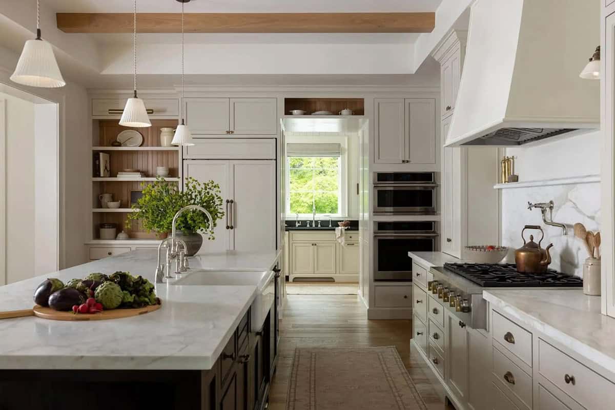 Traditional kitchen with white shaker cabinets, marble island, plaster range hood, and open oak shelving
