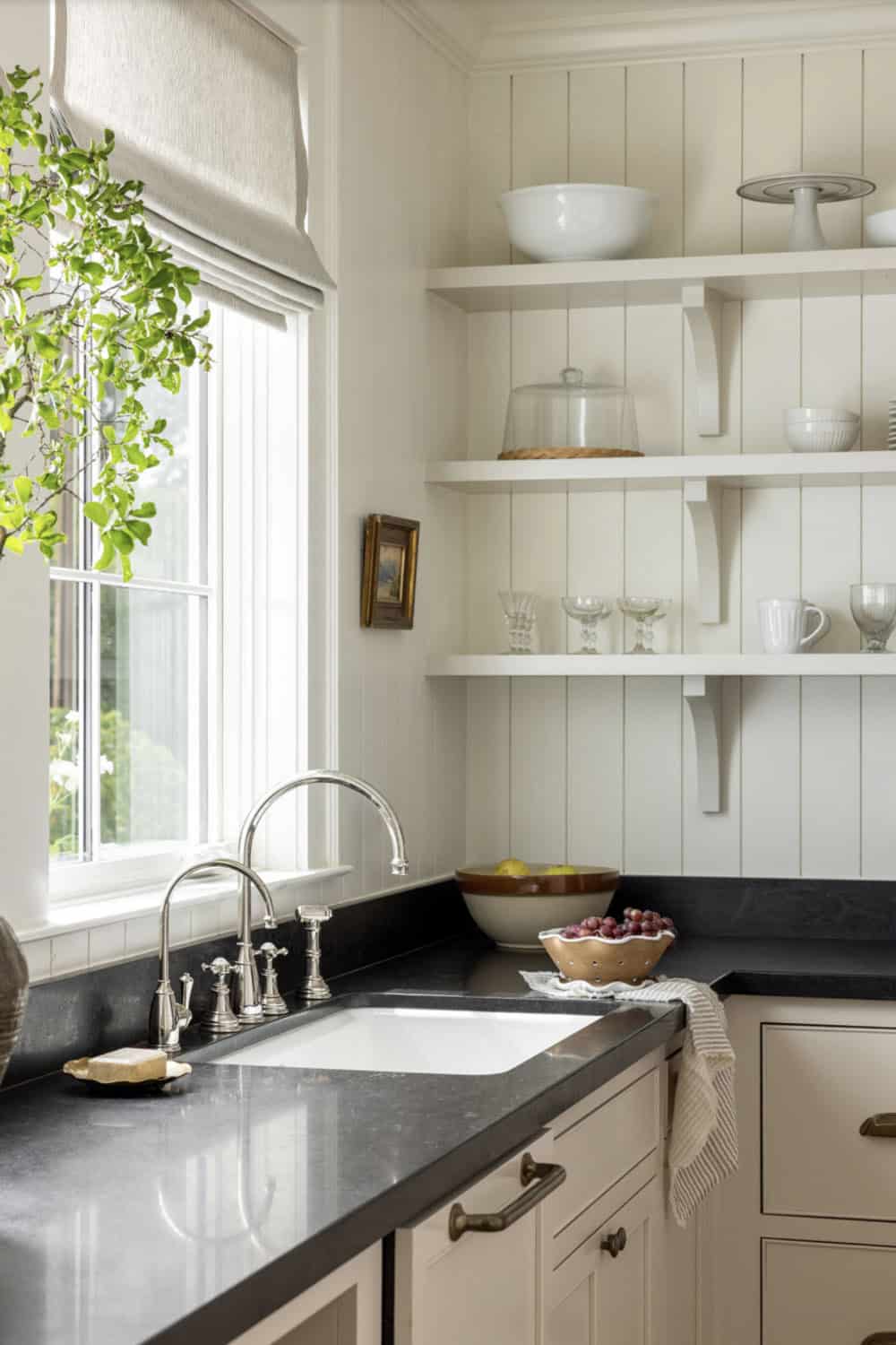 Butler's pantry corner with farmhouse sink, polished nickel faucet, black soapstone countertop, and open shelving