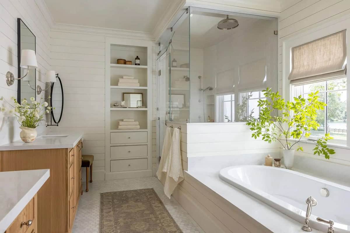 Primary bathroom with shiplap walls, oak vanity, glass shower, soaking tub, and built-in linen storage