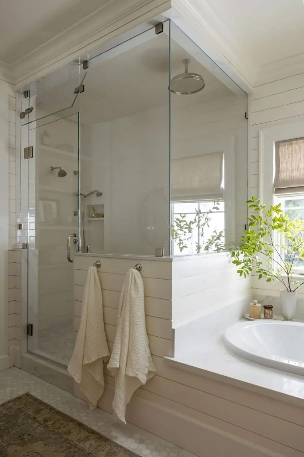 Primary bathroom glass shower enclosure with shiplap walls, soaking tub surround, and garden view window