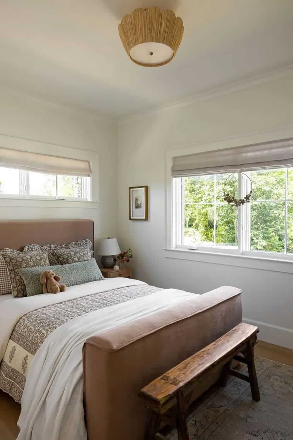 Kid's bedroom with blush upholstered bed, floral bedding, woven flush mount light, and garden views