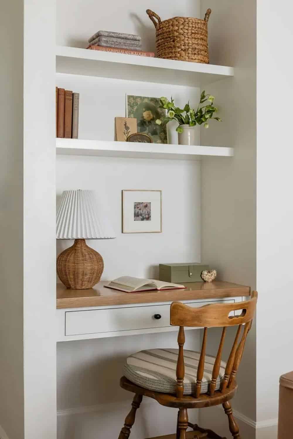 Kid's bedroom built-in desk nook with white floating shelves, wicker lamp, vintage wood chair, and styled books
