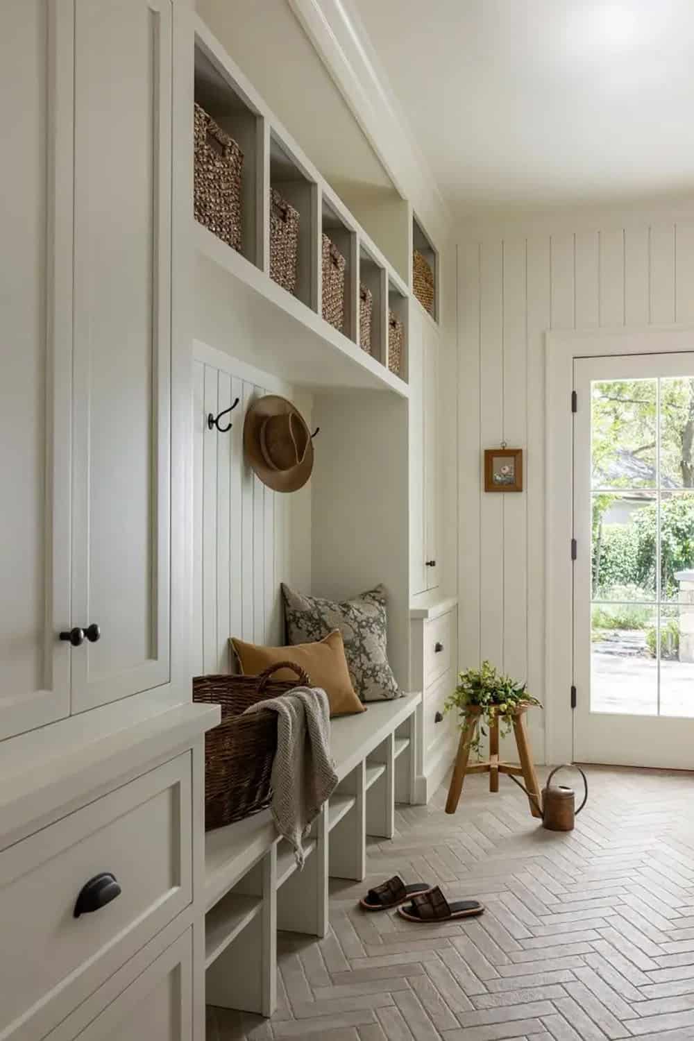 White mudroom with built-in bench, beadboard, coat hooks, and wicker storage baskets