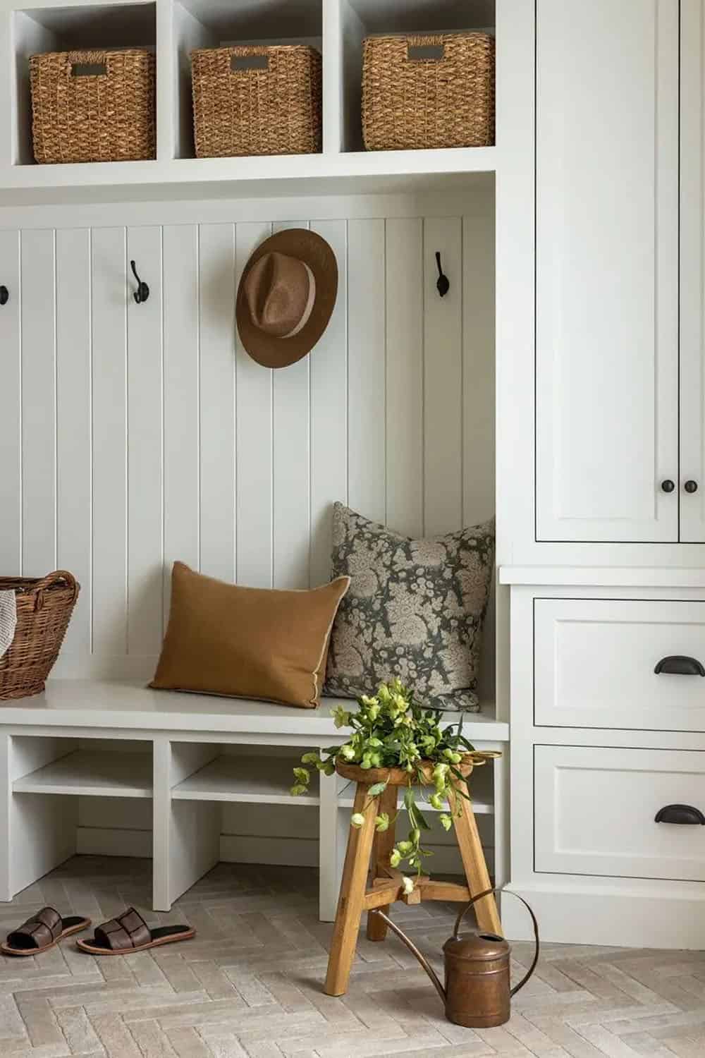 Close-up of mudroom bench with cushions, wicker baskets, and black cabinet hardware