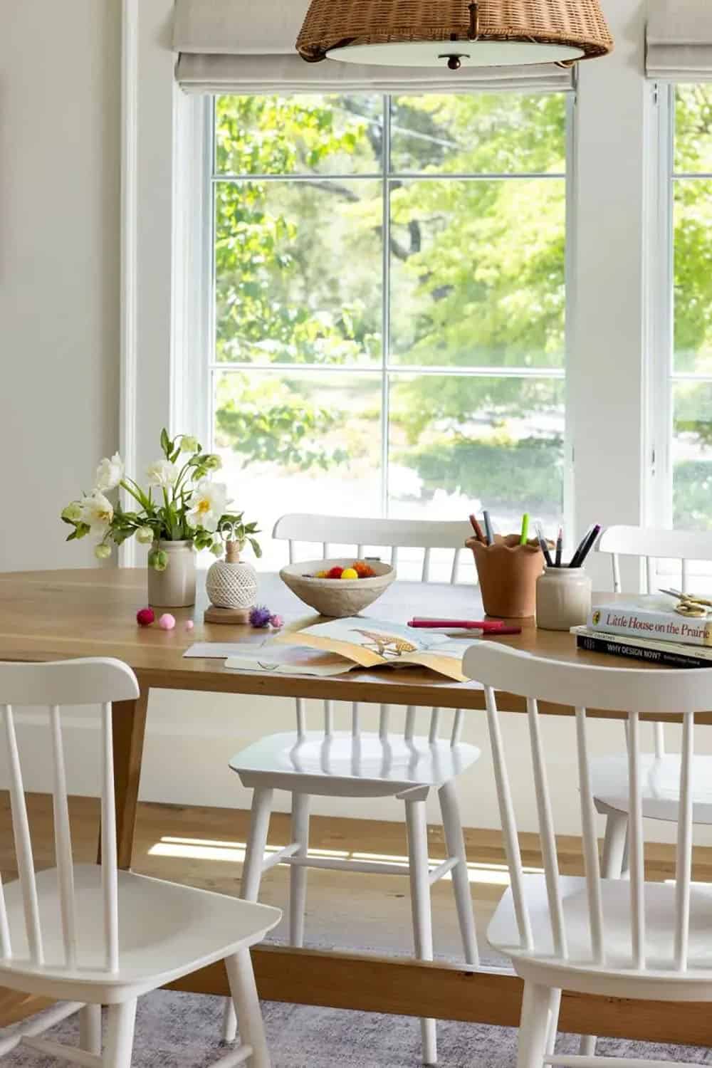 Kids activity table with art supplies, flowers, and Little House on the Prairie book