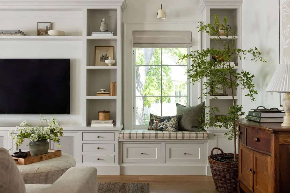 Family room built-in shelving with TV, window seat, and indoor tree in wicker basket