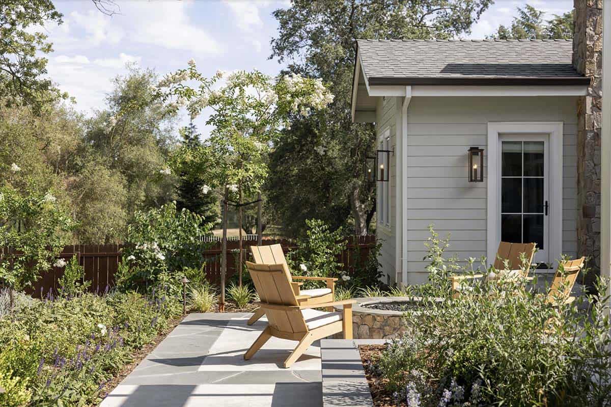 Backyard garden path with wood Adirondack chairs, fire pit, and cottage lantern sconces