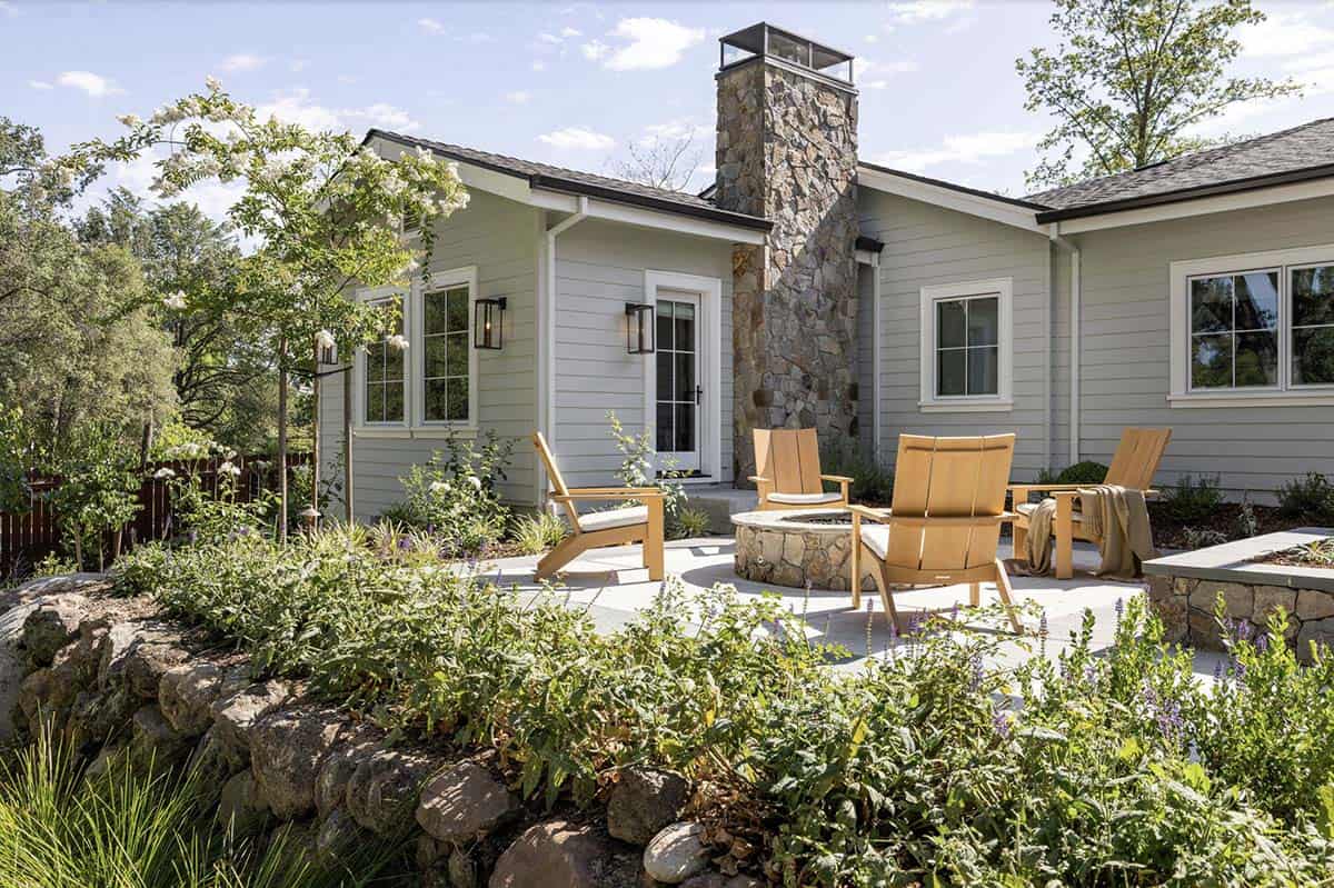 California ranch home exterior with stone chimney, fire pit patio, and lush garden beds