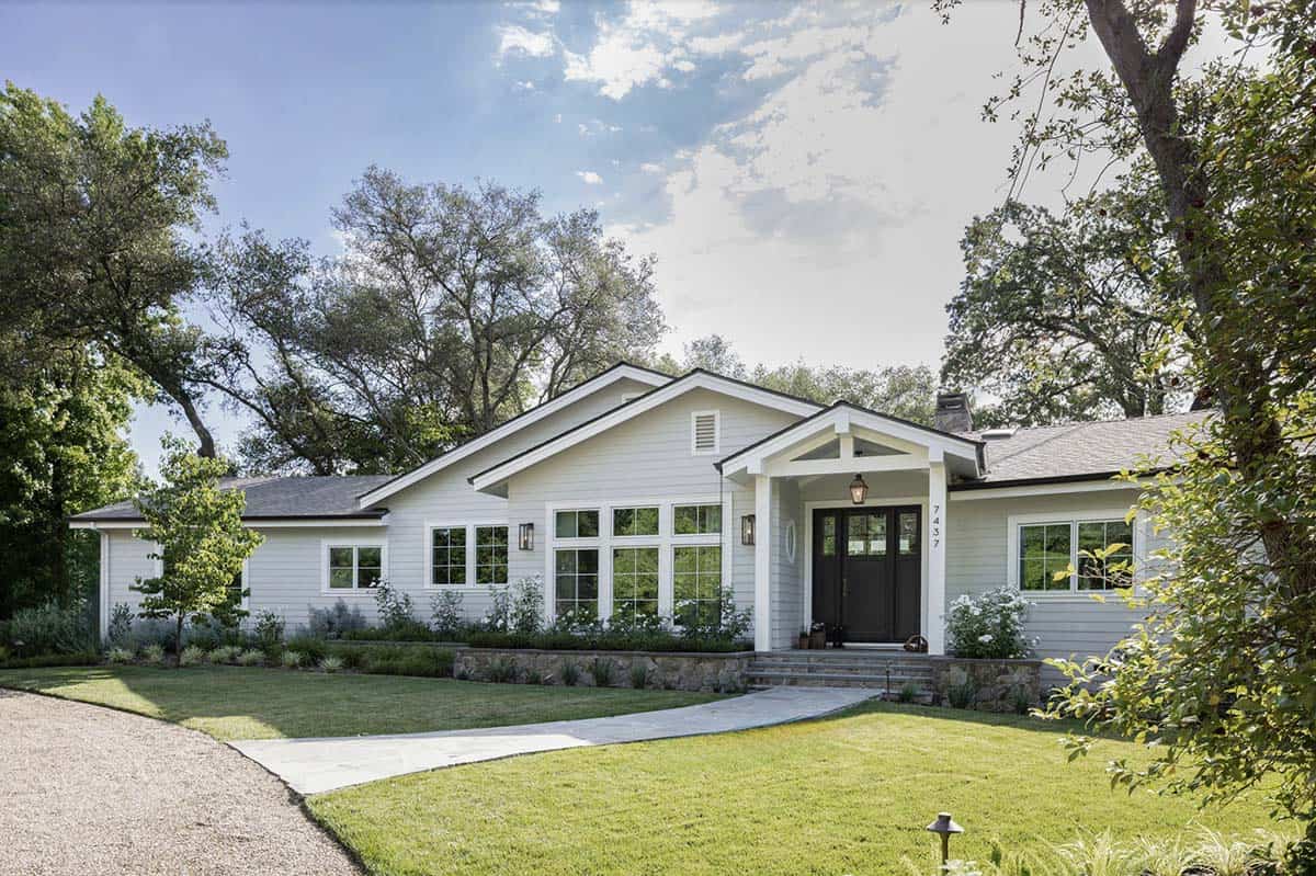 Renovated California ranch home exterior with black double doors and gravel driveway