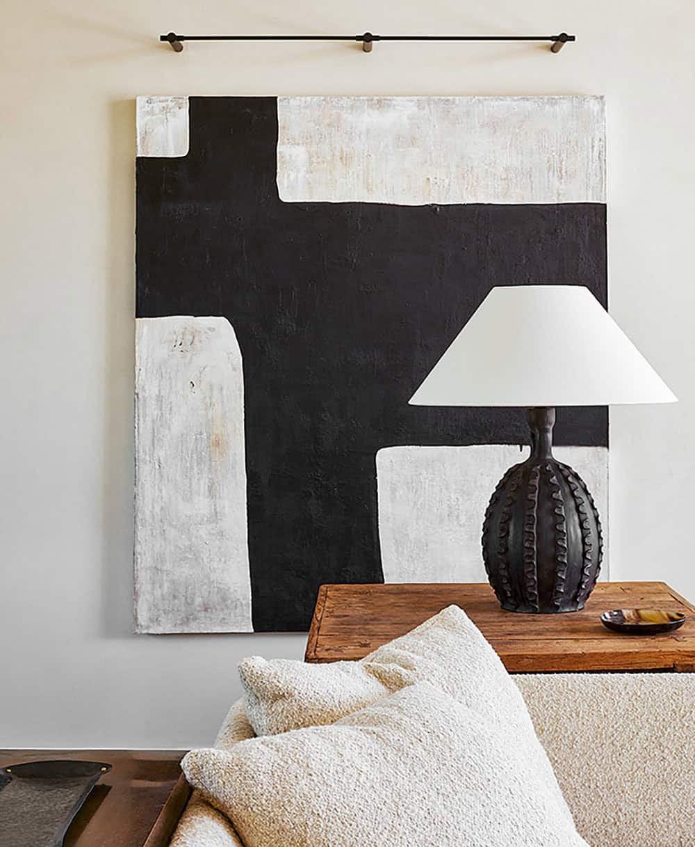 Large black-and-white abstract painting with dark ceramic cactus-form table lamp