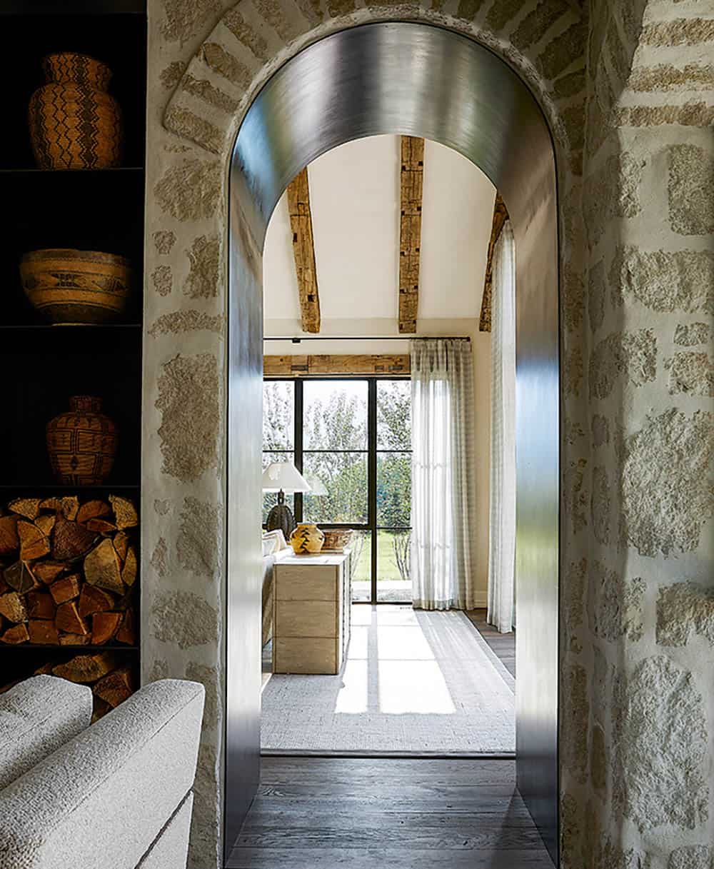 Polished steel-lined arched doorway through stone wall leading to sunlit sitting room
