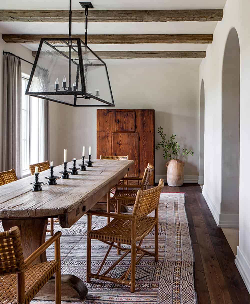 Rustic farmhouse dining room with reclaimed wood table, woven chairs, and iron lantern pendant