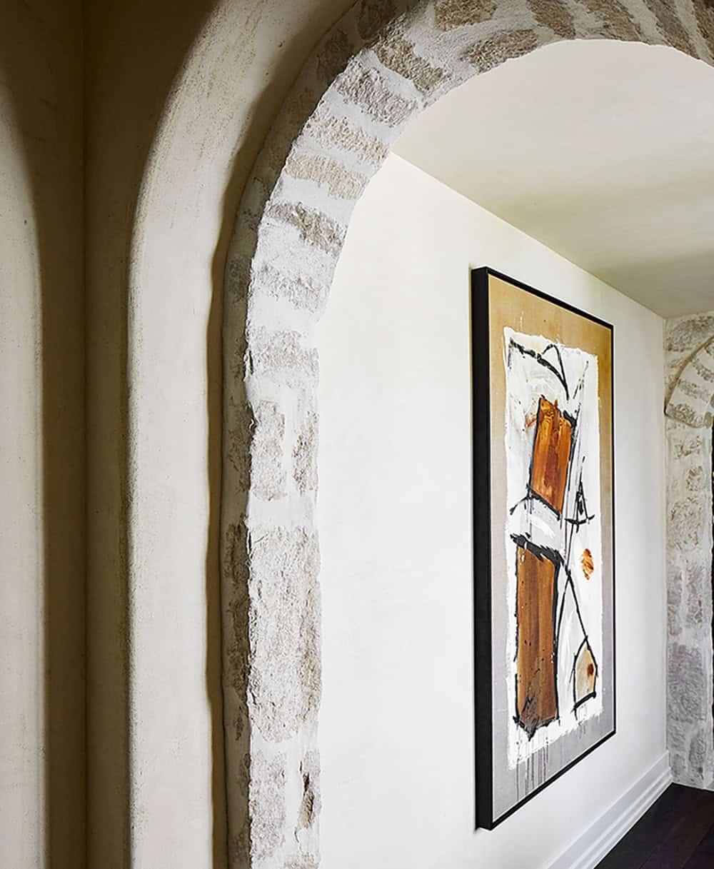 Stone arched hallway with abstract amber-toned artwork in black frame