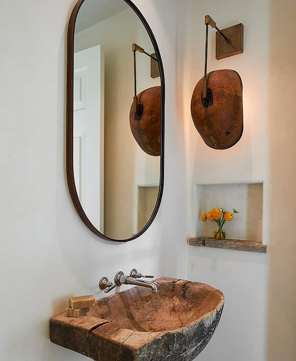 Powder room with live-edge wood vessel sink, oval mirror, hammered copper sconce, and wall niche