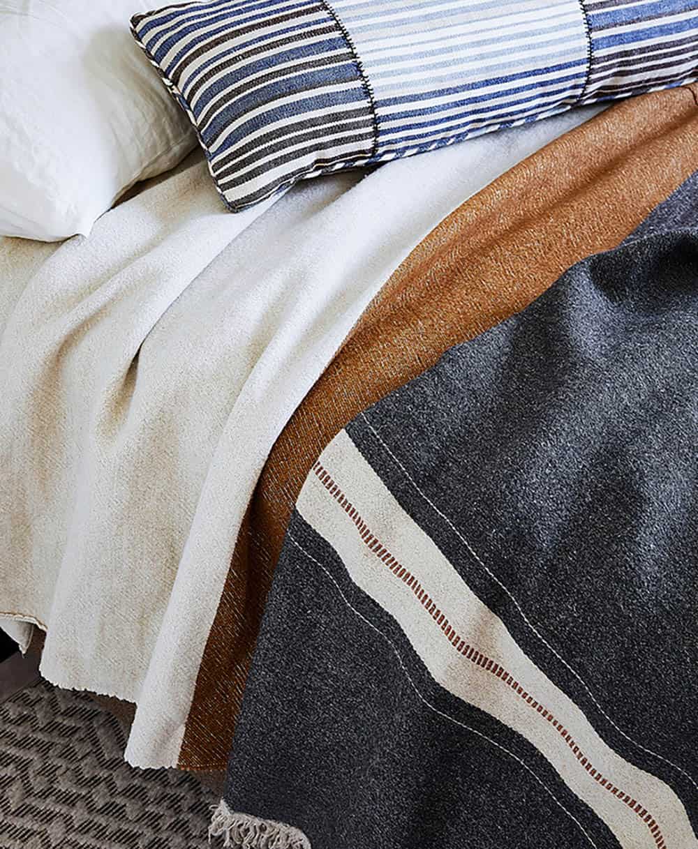 Guest bedroom with vintage snowshoe wall art, leather pommel horse bench, and antique wooden chair