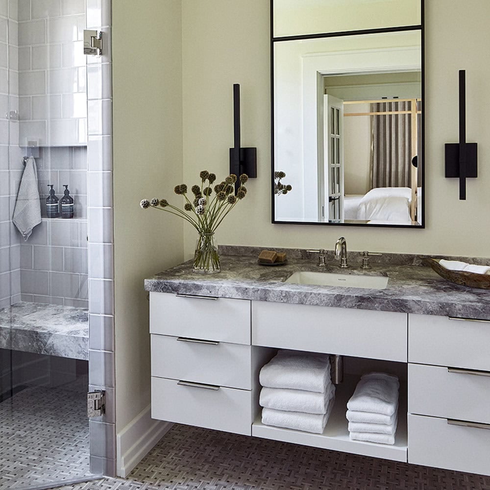 Guest bathroom with floating white vanity, gray marble countertop, black framed mirror, and walk-in shower