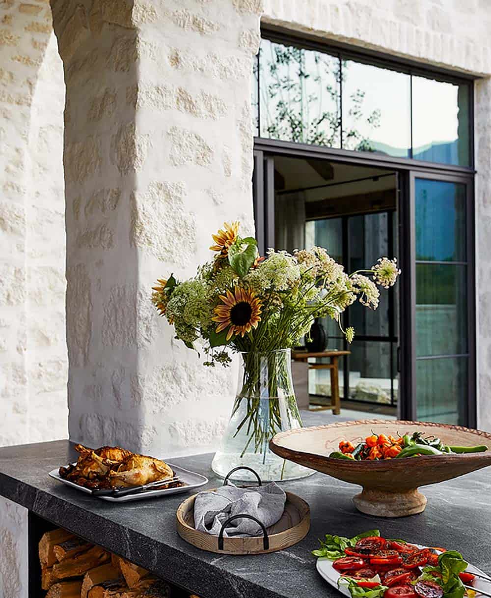 Outdoor kitchen counter with soapstone top, sunflower bouquet, roasted chicken, and grilled vegetables