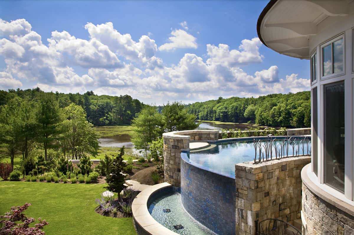 Curved Infinity Pool With Stone Walls and River Views From New Hampshire Estate