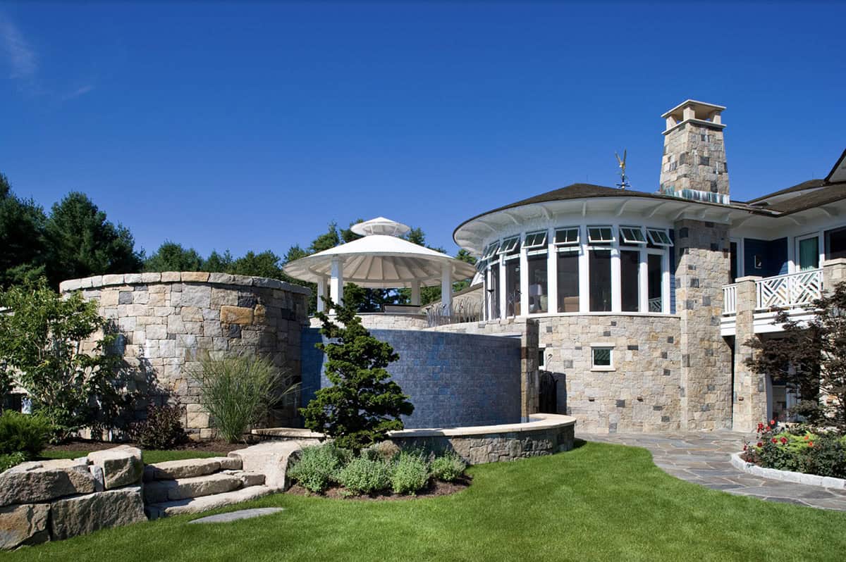 Stone-Walled Backyard With White Gazebo, Curved Pool, and Round Sunroom