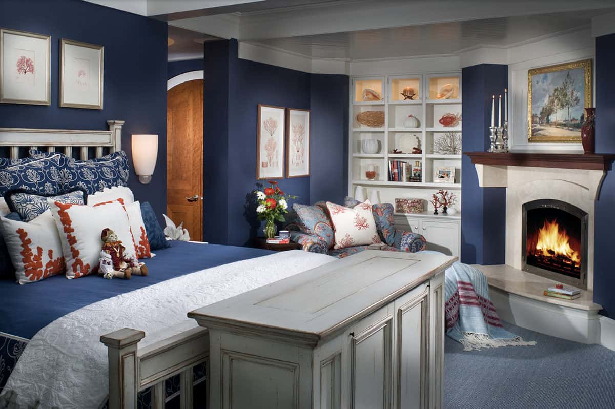 Navy Blue Primary Bedroom With Corner Fireplace, Built-In Shelving, and Coral Accents