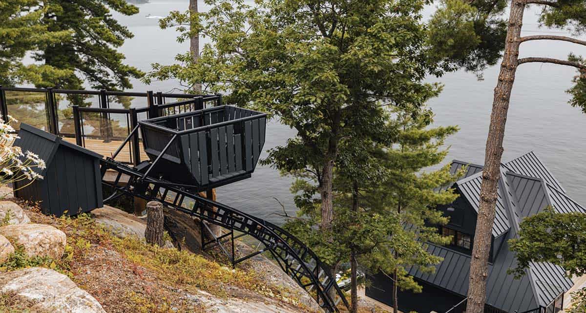 Black funicular gondola on steep hillside track descending toward lake through pine trees
