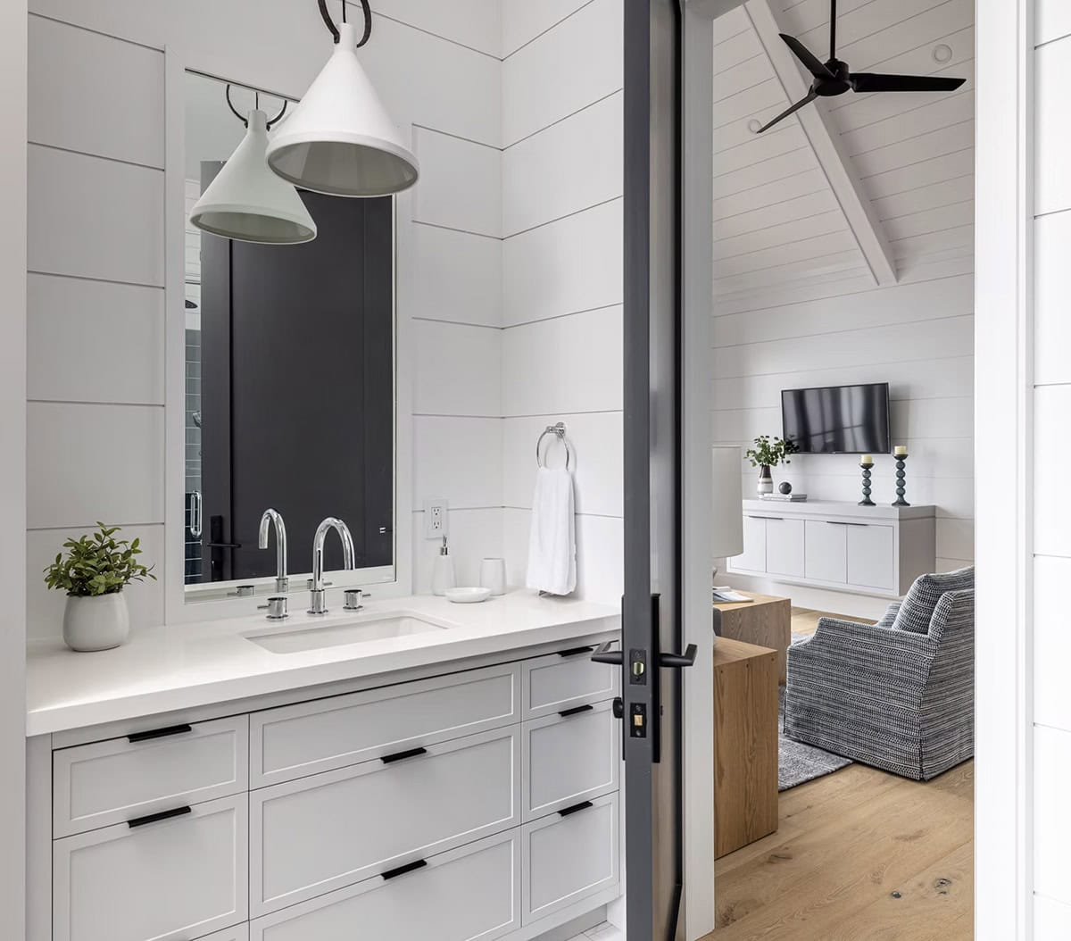 Boathouse bathroom vanity with white cabinetry, pendant light, and view into living area