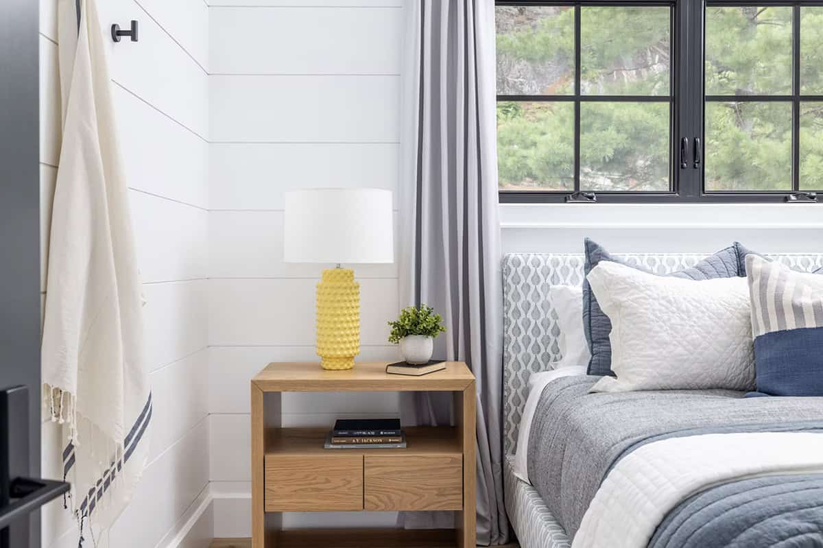 Bedroom nightstand detail with yellow textured lamp, oak side table, and patterned upholstered headboard