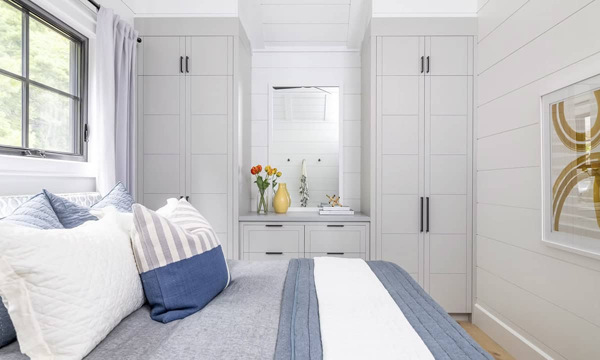 Boathouse bedroom with flanking gray built-in wardrobes and central dresser with mirror