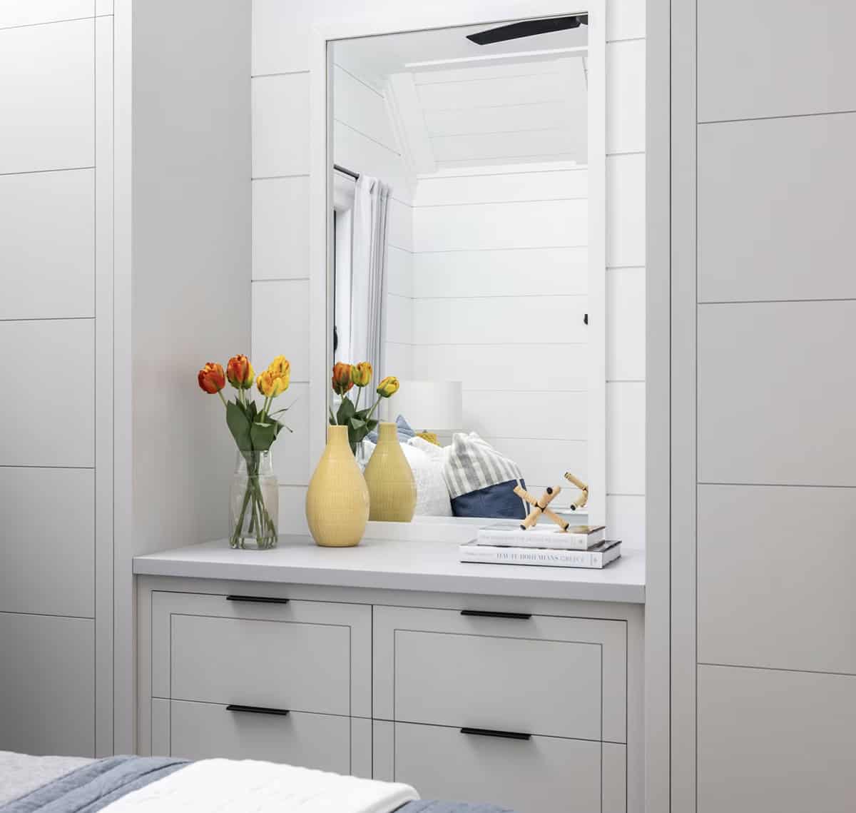 Built-in dresser niche with mirror, orange tulips, and yellow ceramic vase