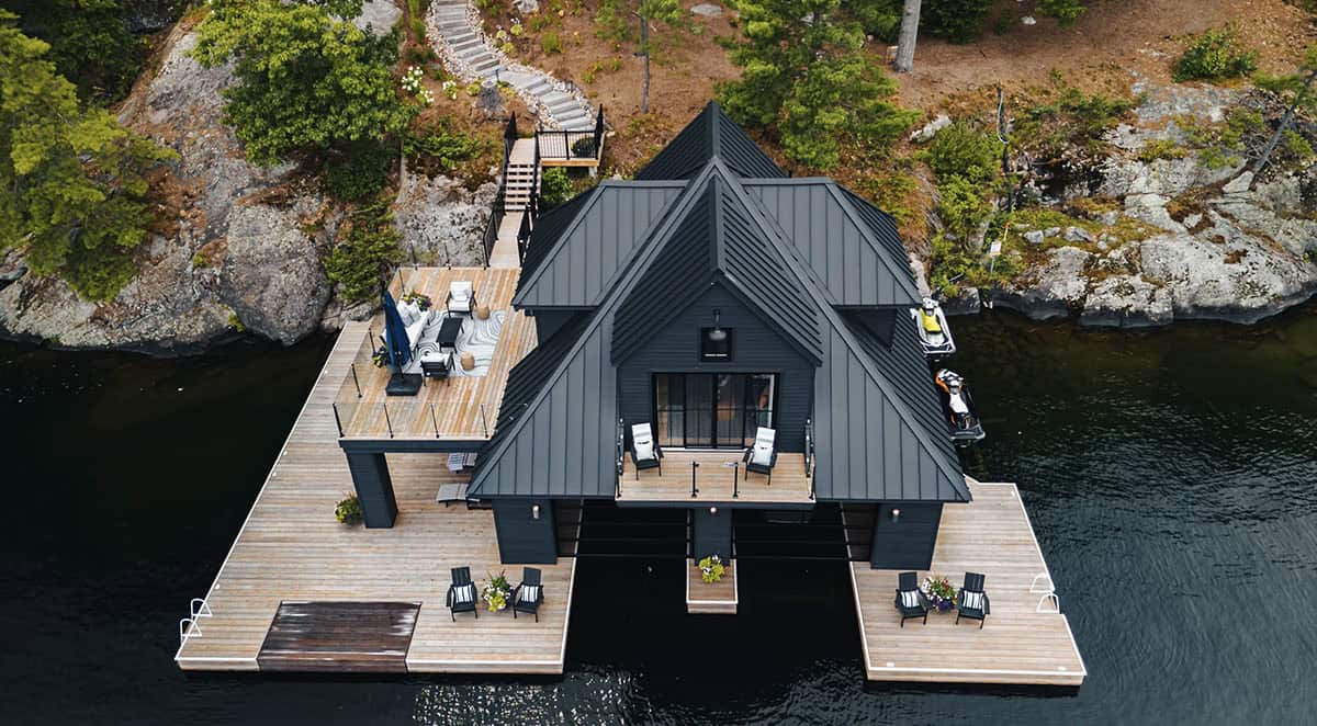 Bird's-eye view of black boathouse rooftop terrace with outdoor seating, lounge chairs, and surrounding cedar docks