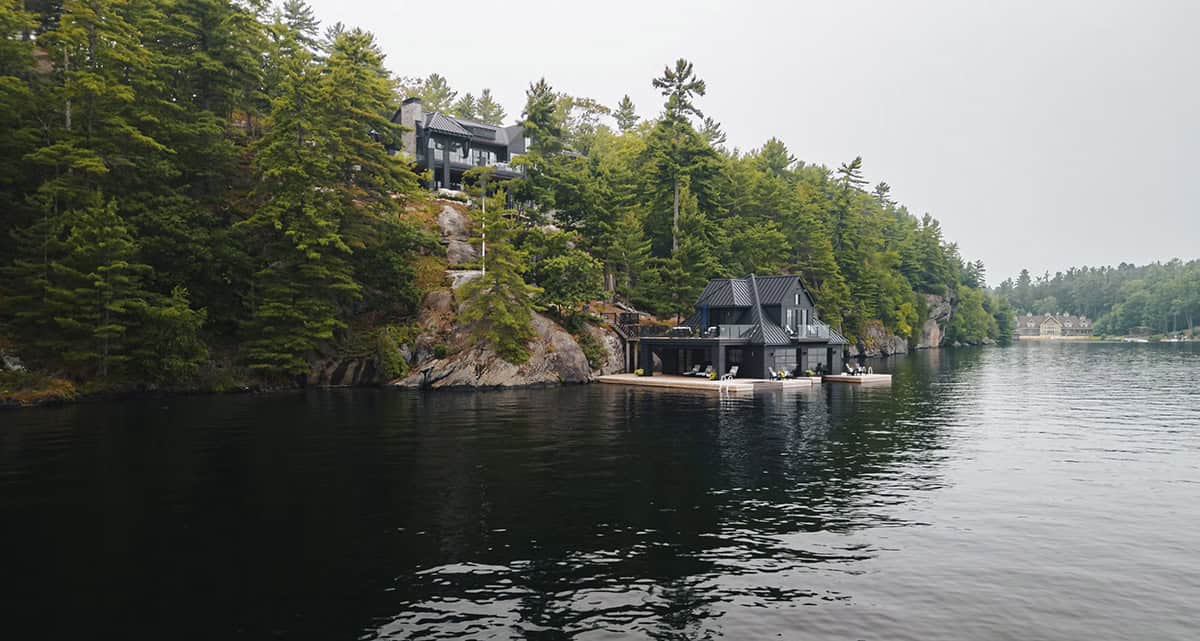 Lake Joseph cottage and boathouse viewed from the water, nestled against Canadian Shield rock and pine forest