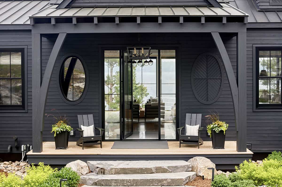 Close-up of cottage entry porch with oval porthole window, circle medallion, and paired Adirondack chairs