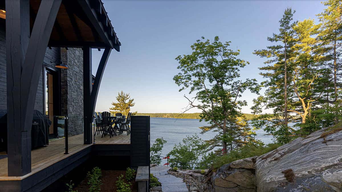 Waterfront deck dining area with lake view through pine trees at golden hour