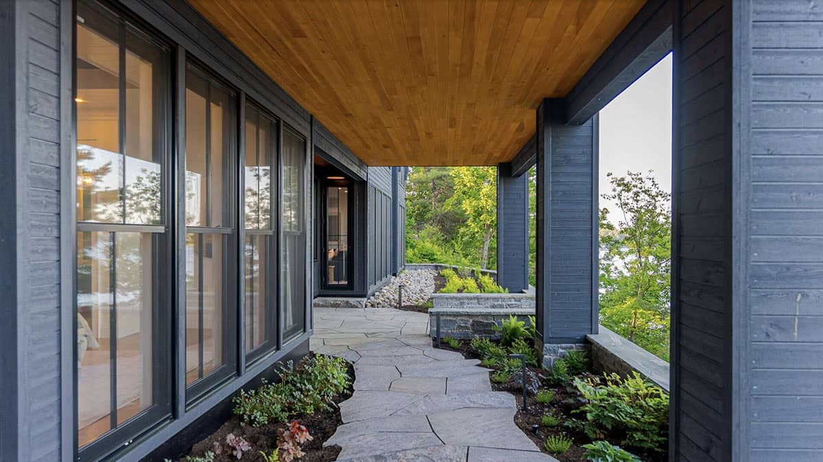 Covered breezeway passage with cedar ceiling, flagstone path, and lush garden plantings