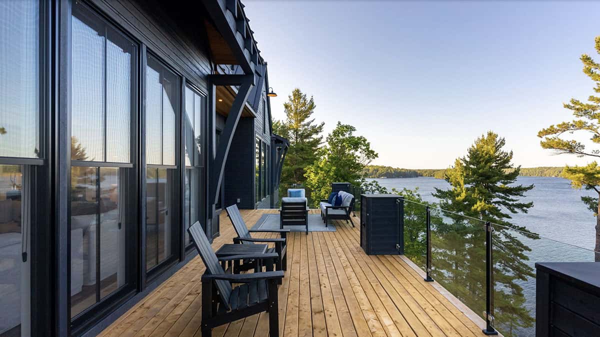 Cedar deck with black Adirondack chairs and panoramic lake view at sunset