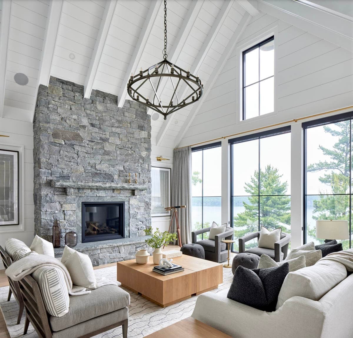 Bright cottage great room with soaring vaulted ceiling, floor-to-ceiling stone fireplace, and lake-view windows