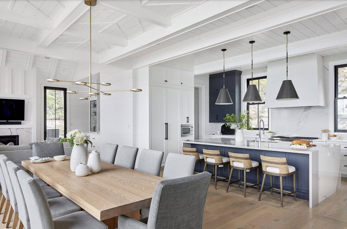 Cottage dining room with oak table, navy kitchen island, brass pendants, and shiplap ceiling