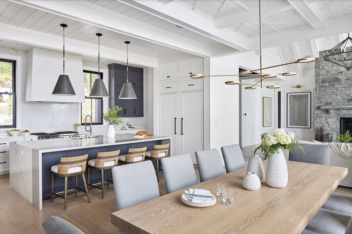 Kitchen and dining area with navy island, woven barstools, marble backsplash, and brass lighting