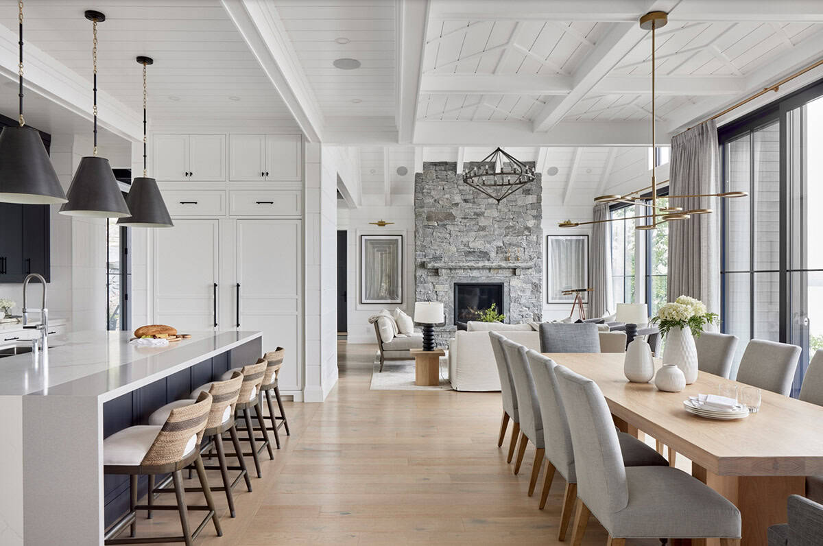 Open-plan kitchen, dining, and living room with navy island, stone fireplace, and white shiplap ceiling