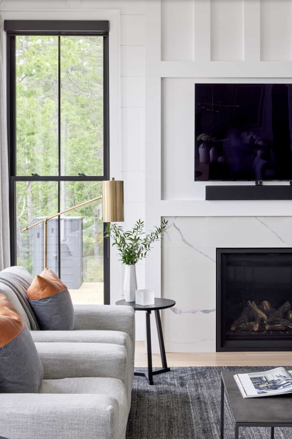 Lower-level family room detail with marble fireplace surround, wall-mounted TV, and leather accent pillow