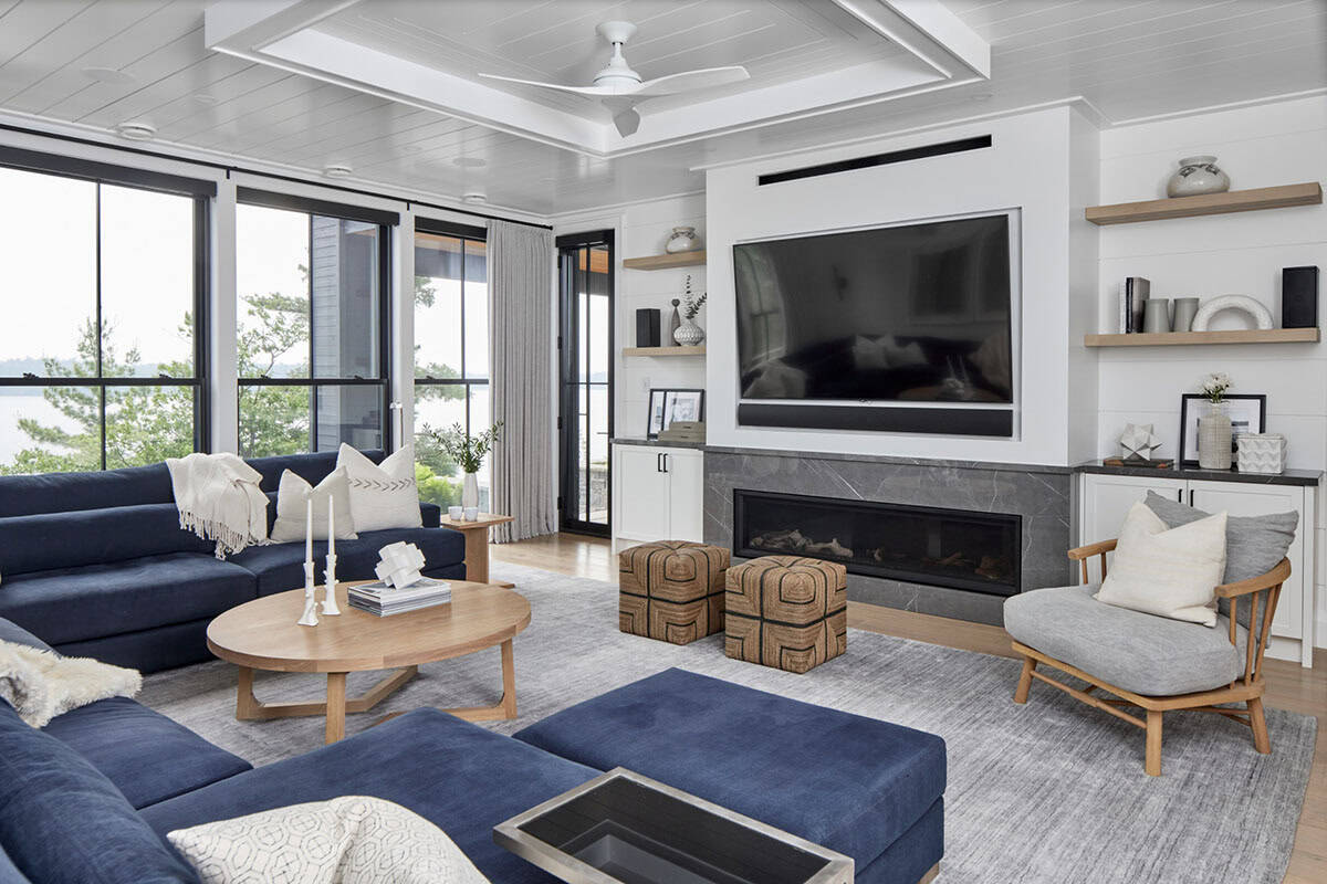 Lower-level media room with navy sectional, grey marble linear fireplace, TV, and coffered ceiling fan