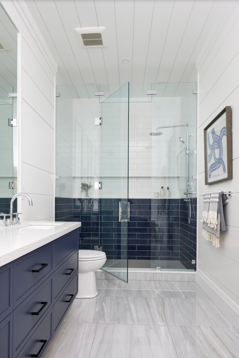 Navy bathroom with glass shower, dark subway tile lower half, white upper tile, and shiplap walls