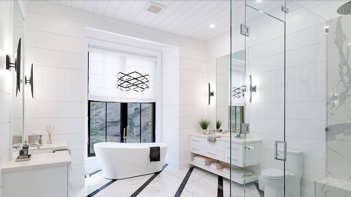 Primary ensuite overview with freestanding tub, geometric black chandelier, glass shower, and marble striped floor