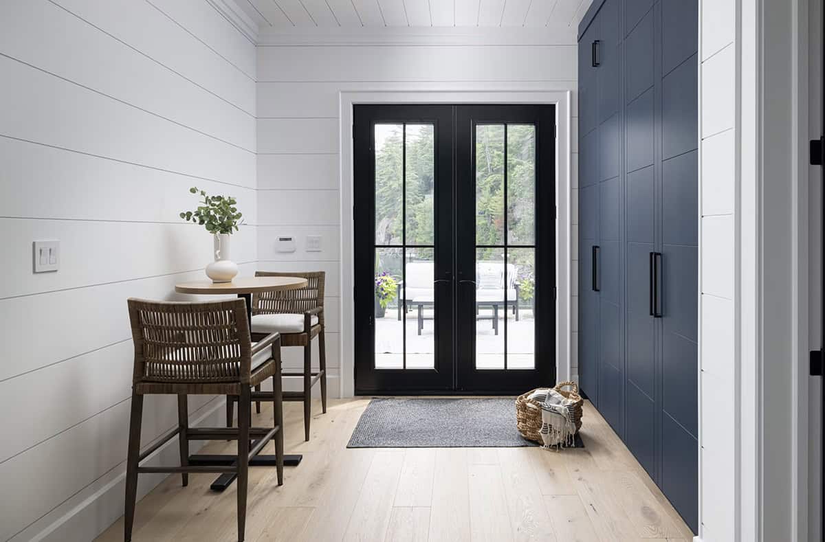 Boathouse entryway with black French doors, navy built-in storage cabinets, and round bistro table