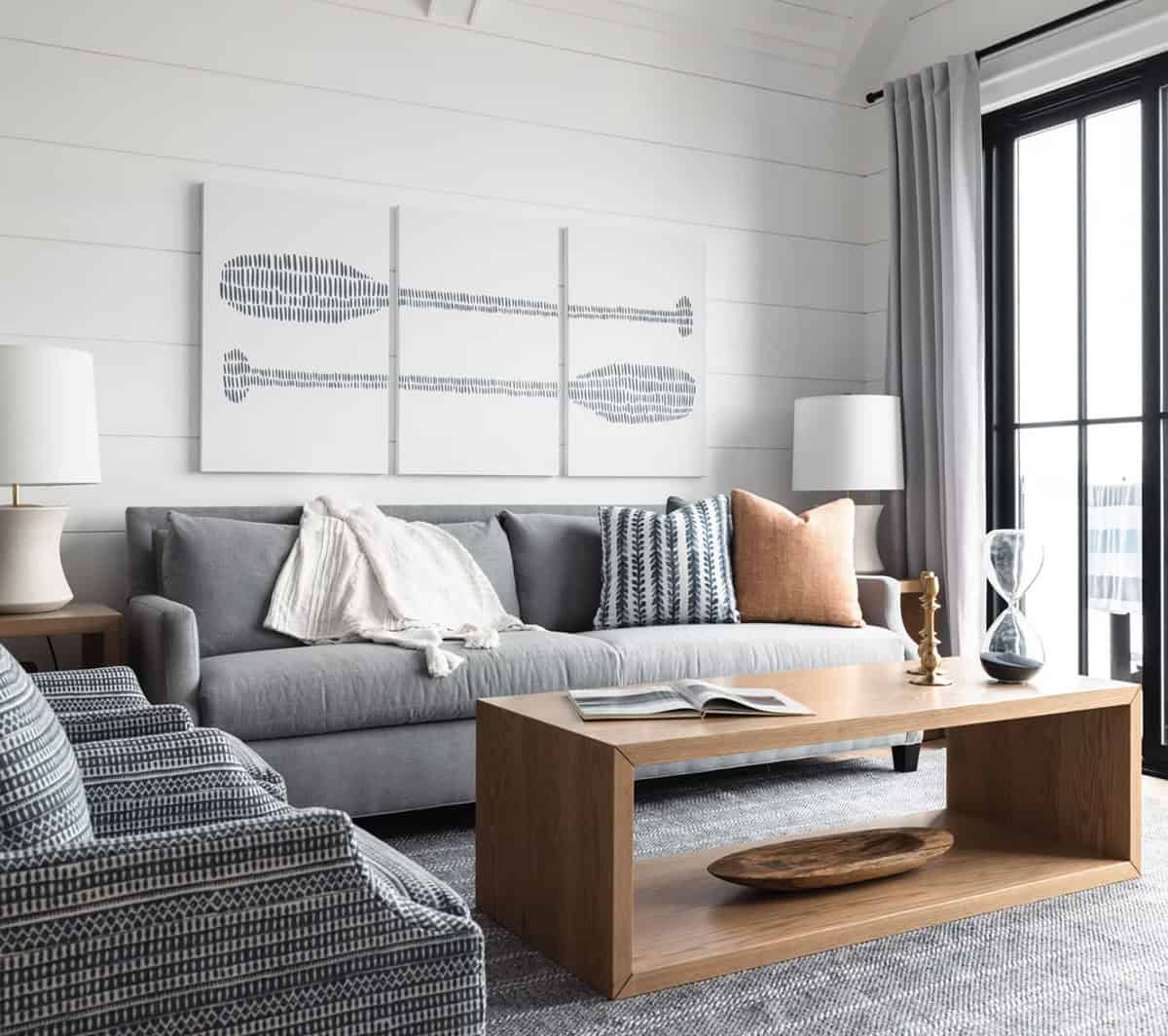 Gray sofa with blue and terracotta pillows, oak coffee table, and abstract paddle triptych artwork