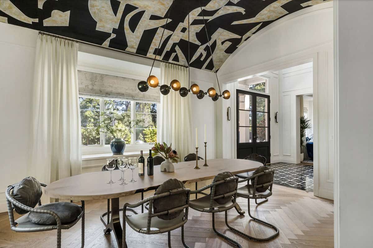 Dining room with dramatic black abstract mural ceiling, globe pendant light, and herringbone hardwood floor