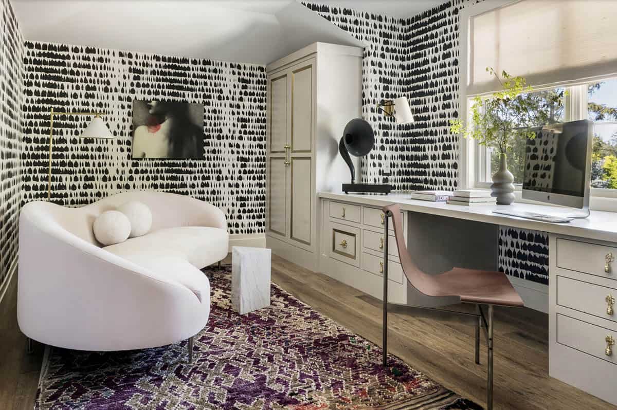 Home office with bold black-and-white graphic wallpaper, curved ivory sofa, and built-in desk with brass hardware