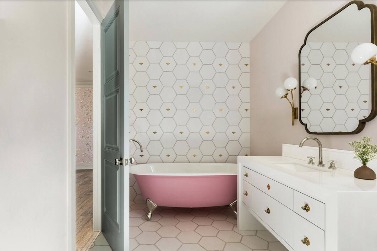 Girl's bathroom with pink clawfoot tub, white hexagon bee-motif wall tiles, and pink hexagon floor tiles