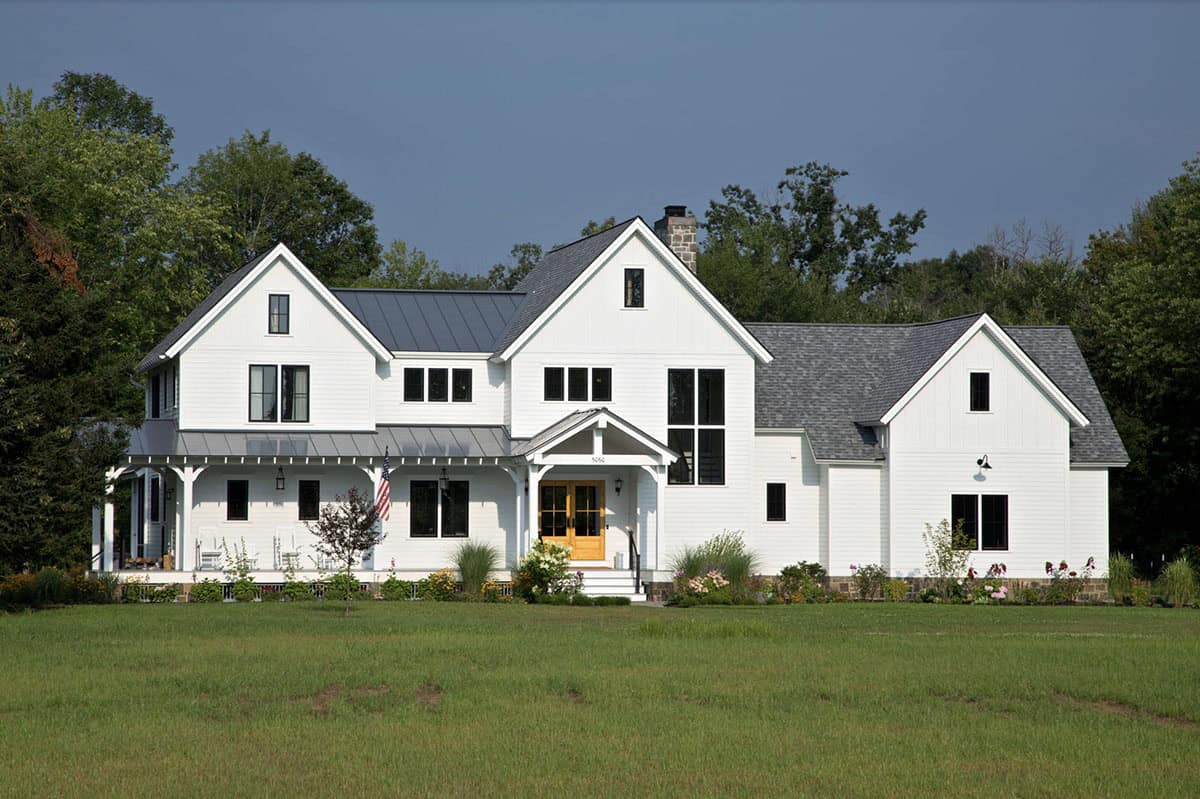 White modern farmhouse exterior with black windows, metal roof, and wrap-around porch